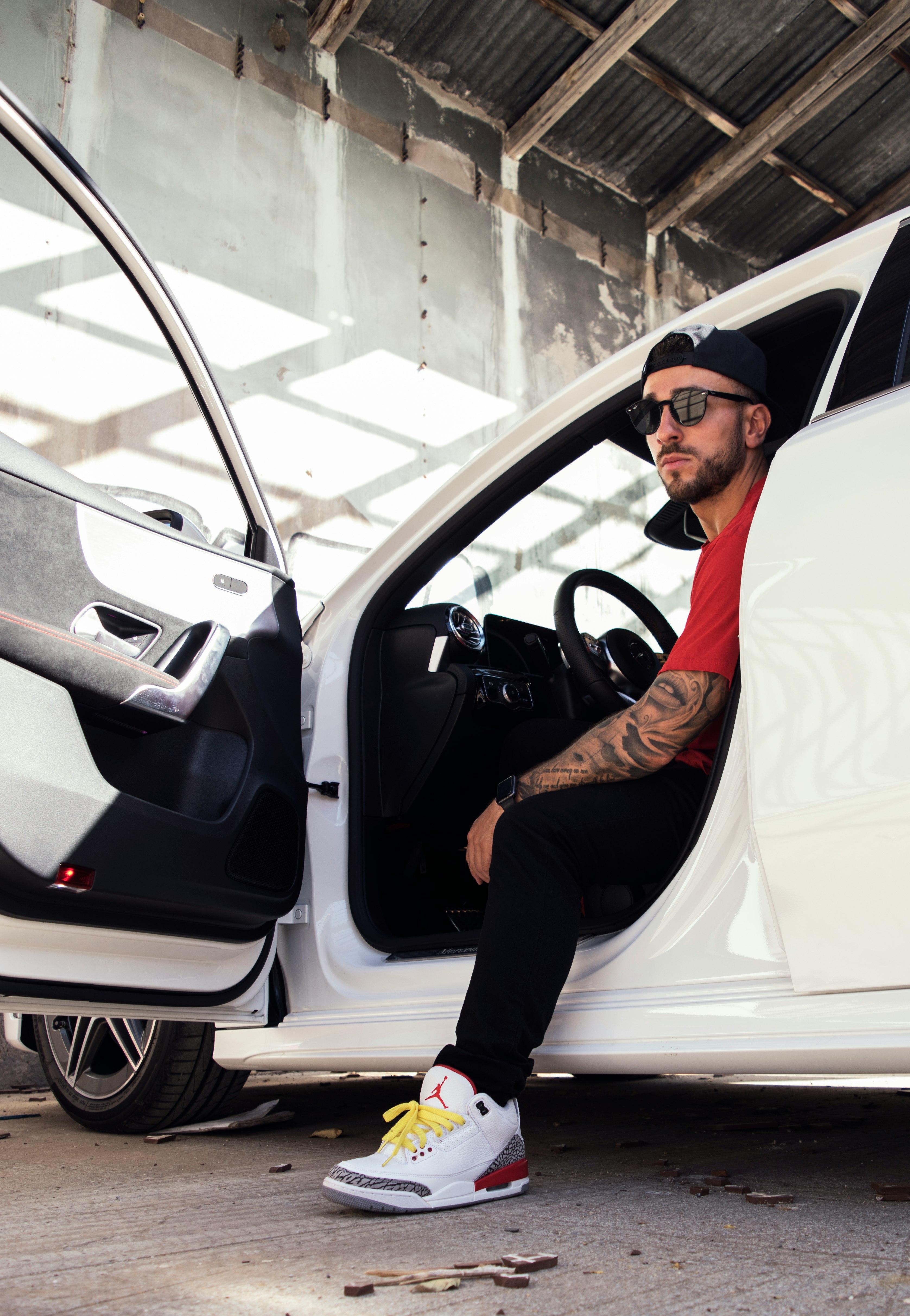 man in orange long sleeve shirt and black pants sitting on white car